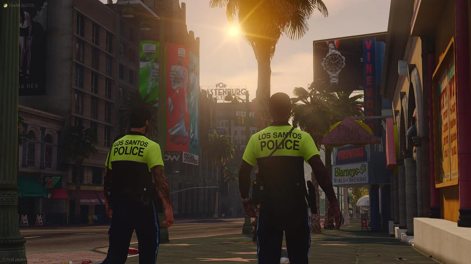 Dua anggota Los Santos Police berpatroli di trotoar Vinewood saat matahari terbenam